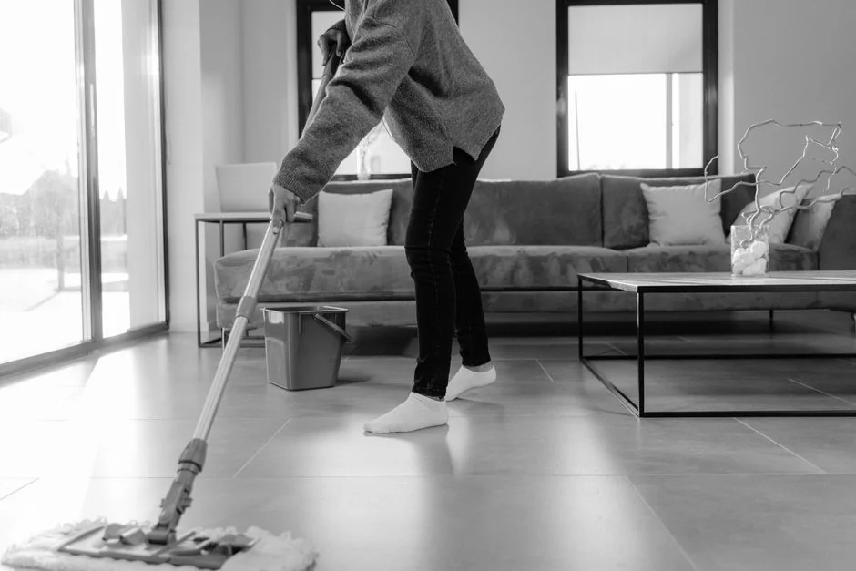 about-us-01 A person cleaning a kitchen shelf with a spray bottle and cloth, keeping it hygienic and spotless.